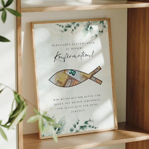 May include: A white card with a watercolor design of green leaves and a fish with a money slot. The card says "Herzlichen Gl&uuml;ckwunsch zu deiner Konfirmation!" and "Wir w&uuml;nschen dir Gl&uuml;ck und Segen auf deinem Lebensweg und alles Gute f&uuml;r deine Zukunft!"