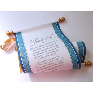 May include: A rolled parchment scroll with a gold ribbon and finials. The scroll has a blue patterned border and contains handwritten text that begins with "My dearest Emily." The scroll is white with gold accents.