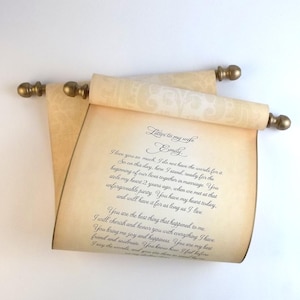 May include: A beige parchment scroll with a decorative pattern, featuring black cursive text titled Letter to my wife Emily. The scroll is held by two wooden rods with rounded gold-colored finials at each end, creating a classic display.