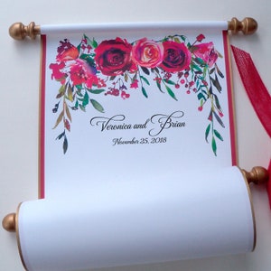 May include: A white scroll with a red and green floral design at the top. The scroll is rolled up and tied with a red ribbon. The text "Veronica and Brian" and "November 25, 2018" is printed on the scroll.