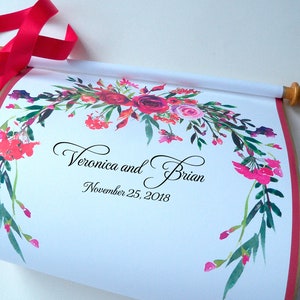 May include: A white scroll with a floral design in shades of pink, red, and green. The scroll is tied with a red ribbon and has the text "Veronica and Brian, November 25, 2018" printed on it.