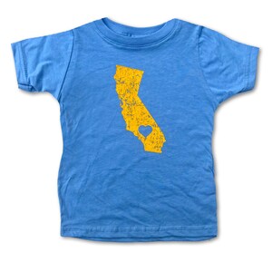 May include: A light blue t-shirt with a yellow outline of the state of California with a small heart inside. The heart is also yellow.
