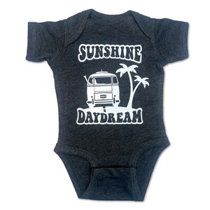 May include: A dark grey baby onesie with a white graphic of a vintage van with the words "Sunshine Daydream" above it.