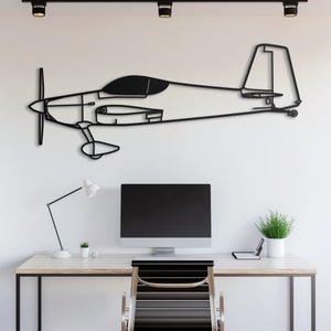 May include: A black metal airplane wall art piece. The art features a detailed outline of a propeller plane, mounted on a white wall. The plane's design includes the propeller, cockpit, wings, and tail. The art is above a desk.