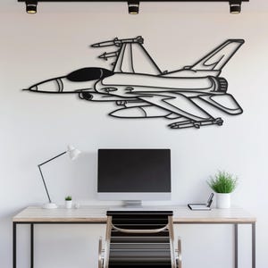 May include: Black metal wall art depicting a fighter jet with missiles. The artwork is a detailed outline of the aircraft, showcasing its wings, tail, and cockpit. The jet is mounted on a white wall, creating a striking contrast.
