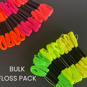 May include: A collection of neon embroidery floss bundles in vibrant colors: orange, pink, and yellow-green. Each bundle has a black base. The text "BULK FLOSS PACK" is displayed in white at the bottom of the image.