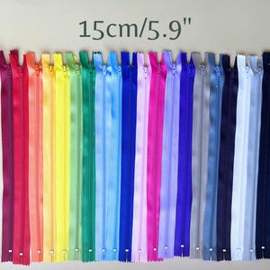 May include: A collection of colorful zippers, each 5.9 inches (15 cm) long, arranged in a rainbow spectrum. The zippers span a range of colors, from deep burgundy to light blue and white. The image includes the text "15cm/5.9" at the top.