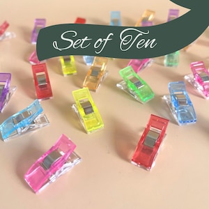 May include: Set of ten colourful plastic clips for sewing or crafting. The clips are translucent and have a metal spring.