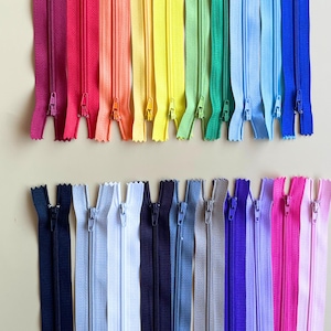 May include: A selection of colourful zips in a rainbow of shades, including red, orange, yellow, green, blue, and purple. The zips are arranged in two rows, with a variety of colours and shades.