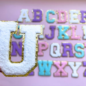 May include: White felt letter U with a gold outline. The letter is part of a set of alphabet letters in various pastel colours with gold outlines.
