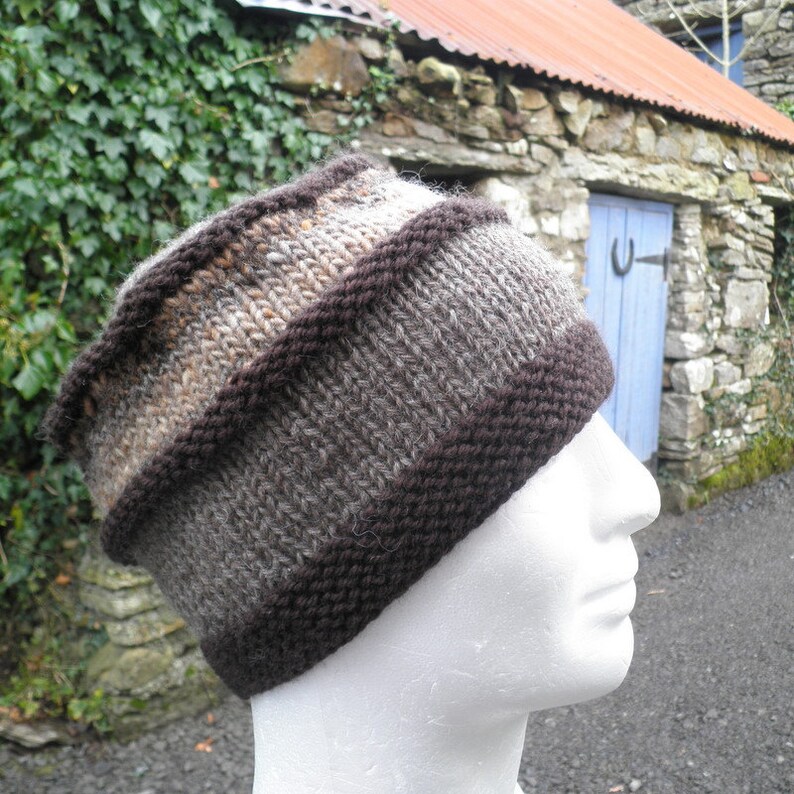 May include: A brown and gray knitted hat with a brown band. The hat is made of wool and has a textured surface.