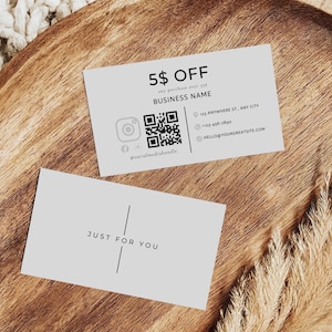 Puede incluir: Dos tarjetas de visita de color gris claro sobre una superficie de madera. Una tarjeta tiene el texto "5$ OFF" y un código QR. La otra tarjeta dice "JUST FOR YOU". Las tarjetas también incluyen identificadores de redes sociales e información de contacto.