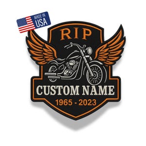 Puede incluir: Un parche bordado en forma de escudo con una motocicleta con alas naranjas, el texto RIP, CUSTOM NAME y 1965-2023 en hilo naranja y blanco sobre fondo negro. Una pequeña etiqueta rectangular muestra la bandera de EE. UU. y MADE IN USA.