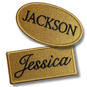 May include: Two embroidered name patches. One is an oval shape with the name "JACKSON" in black script. The other is a rectangle with the name "Jessica" in black script. Both patches are gold.