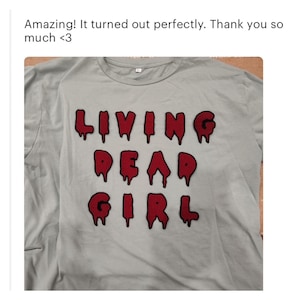 May include: A light blue t-shirt with the words "LIVING DEAD GIRL" in red dripping letters.