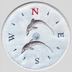 Puede incluir: Brújula bordada blanca con dos delfines grises saltando fuera del agua. Los puntos de la brújula están etiquetados con N, S, E y W.