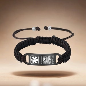 Op de afbeelding: Zwart gevlochten armband met een zwart metalen label met een medisch symbool, een QR-code en de tekst "HEALTH INFO" en "SCAN ME".