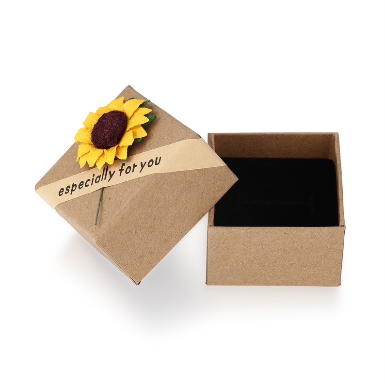 May include: A brown cardboard gift box with a black velvet interior, open to reveal its contents. The lid is adorned with a yellow sunflower and a banner that reads "especially for you."