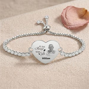Op de afbeelding: Een zilveren armband met een hartvormige hanger. De hanger heeft een foto van een man, de woorden "I Am Always With You" en de naam "William". De armband is versierd met heldere kristallen.