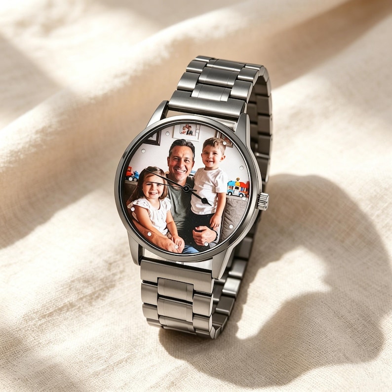 May include: A silver-toned metal wristwatch featuring a custom circular watch face that displays a color photograph of an adult and two children. The timepiece has a linked metal band, a round case, and thin black hands for indicating the time.