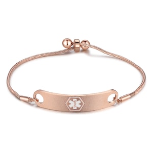 May include: A rose gold medical alert bracelet with a white medical symbol and the text "911" on a curved tag. The bracelet has a snake chain style and an adjustable clasp.
