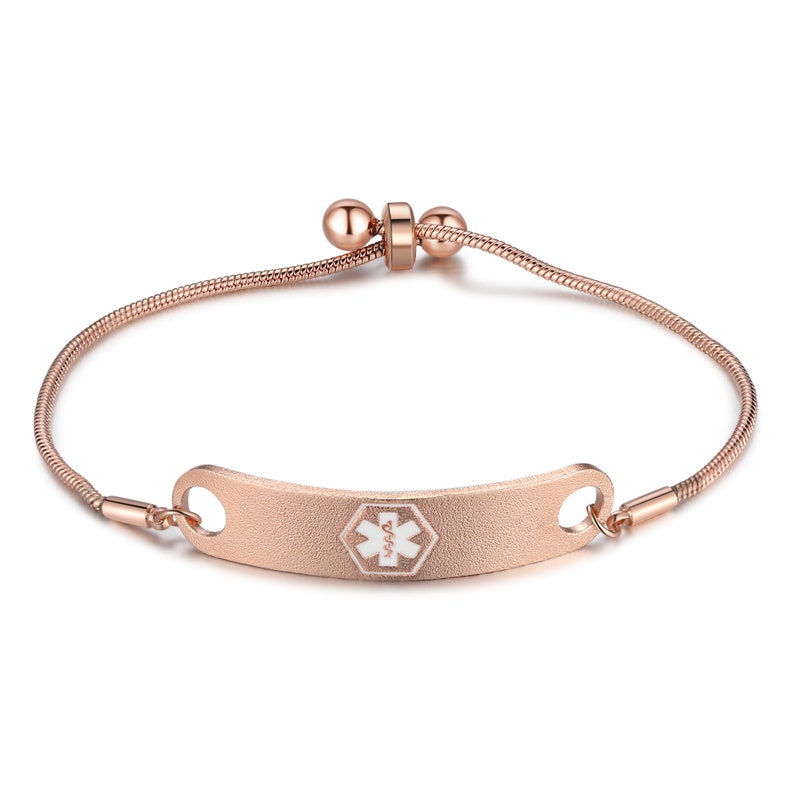 May include: A rose gold medical alert bracelet with a white medical symbol and the text "911" on a curved tag. The bracelet has a snake chain style and an adjustable clasp.