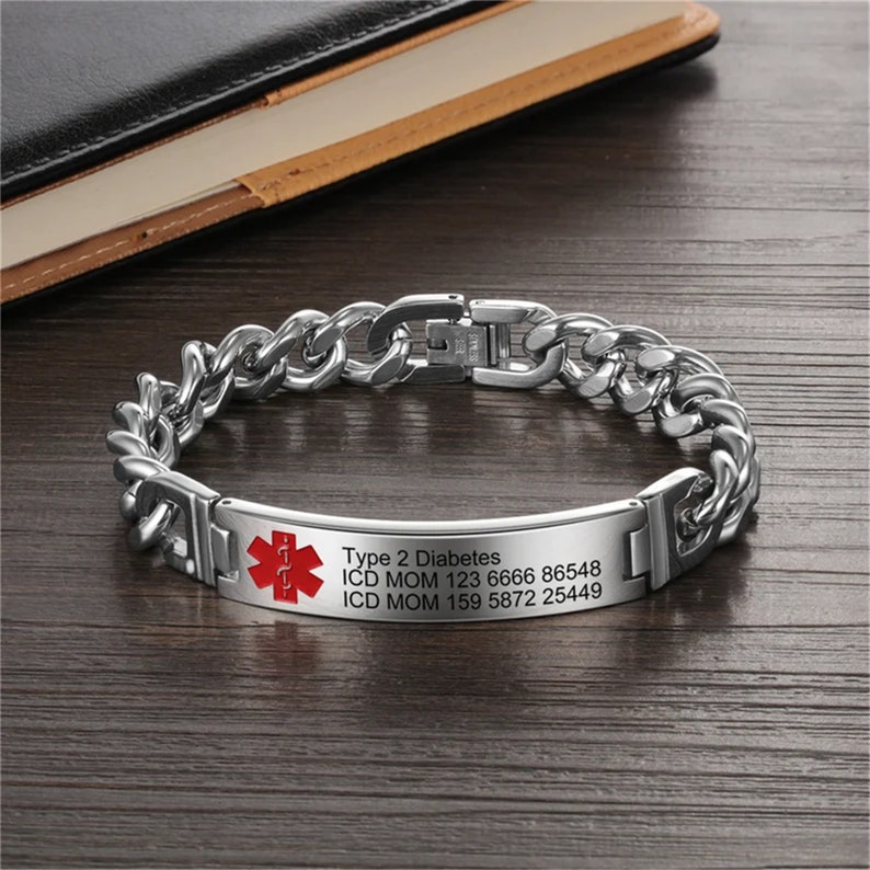 May include: A silver chain bracelet with a medical alert tag. The tag has a red star of life symbol and the text "Type 2 Diabetes, ICD MOM 123 6666 86548, ICD MOM 159 5872 25449".