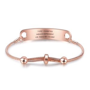 May include: Rose gold medical alert bracelet with a personalized engraved tag that reads "TYPE 1 DIABETES INSULIN DEPENDENT ICE: Adiana 801-123-4567".