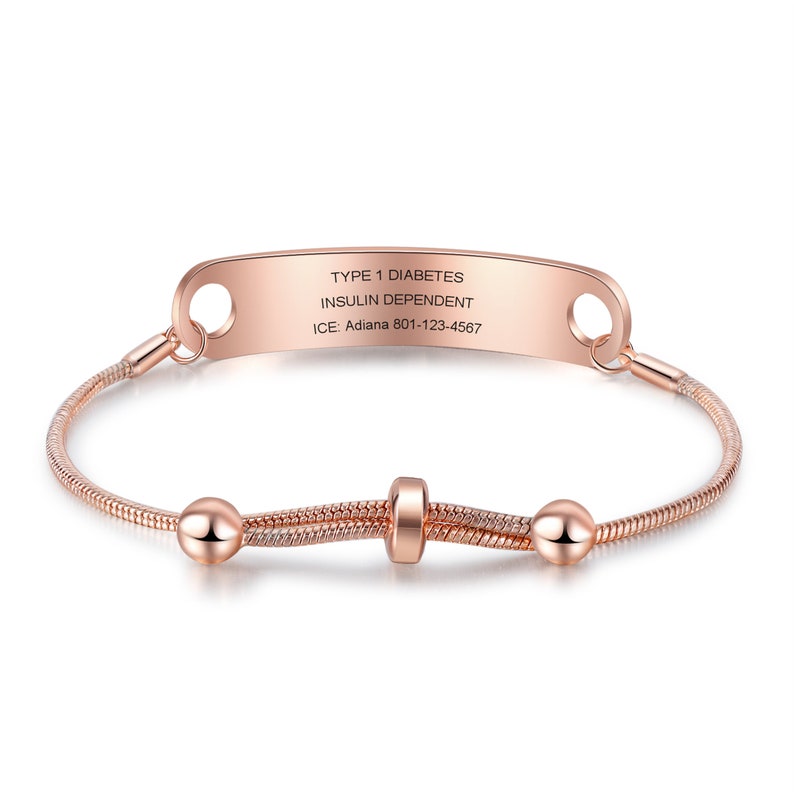 May include: Rose gold medical alert bracelet with a personalized engraved tag that reads "TYPE 1 DIABETES INSULIN DEPENDENT ICE: Adiana 801-123-4567".