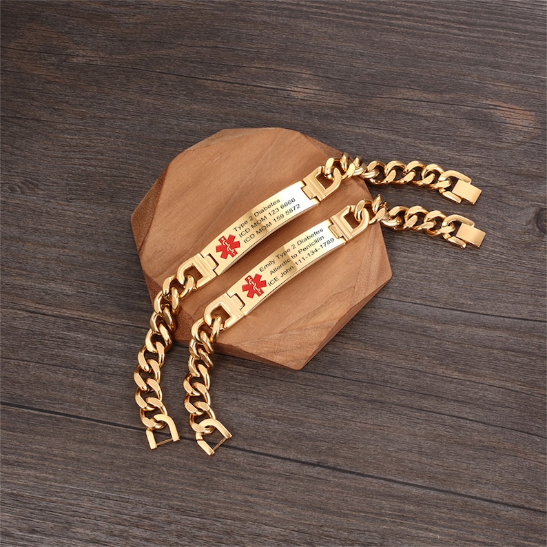 May include: Two gold chain bracelets with medical alert tags. The tags are engraved with medical information, including the type of diabetes, ICD codes, and allergy information. The tags have a red medical symbol.