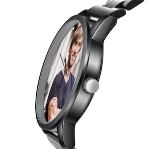May include: A black wristwatch with a circular case and a matching black link band. The watch face features a custom photographic print of a person with long brown hair wearing a dark blue shirt, with thin black hour and minute hands.
