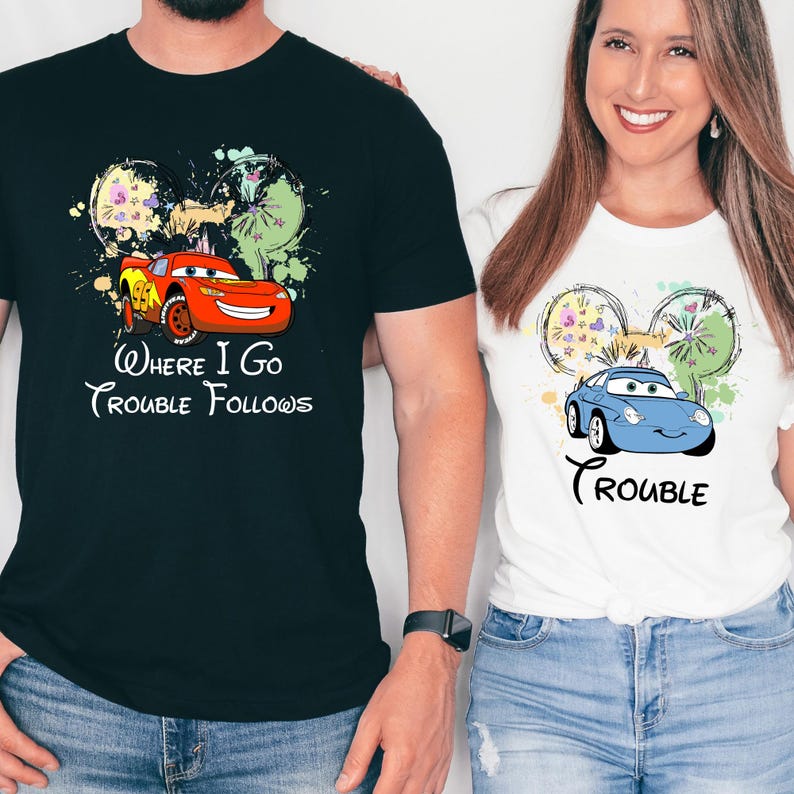A man and a woman are standing next to each other, both wearing t-shirts with Disney-themed designs.