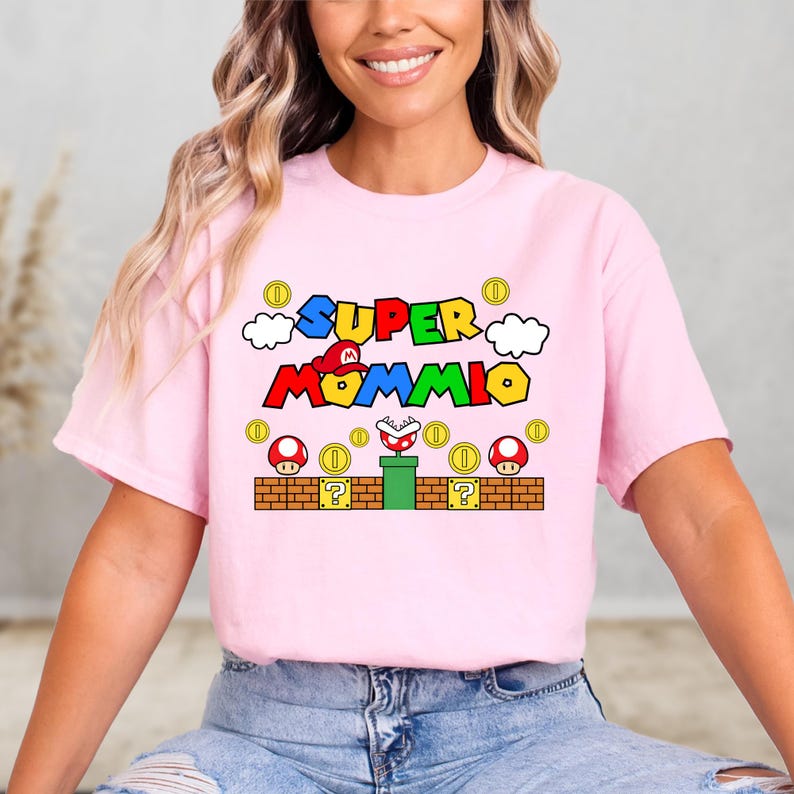 A woman wearing a pink t-shirt with a colorful graphic design featuring a character from the Super Mario video game franchise.