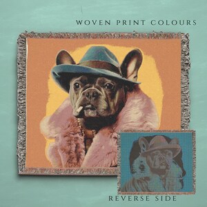 May include: A woven tapestry featuring a French Bulldog wearing a blue hat and a pink fur coat. The tapestry has a light orange background and the text "WOVEN PRINT COLOURS" at the top. The reverse side of the tapestry is shown in a smaller image below, with a blue background.