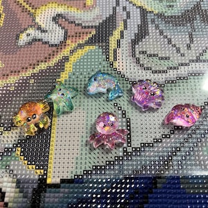 以下が含まれることがあります： カラフルな樹脂製の海の生き物の置物6個セット。置物には、カニ、ヒトデ、イルカ、クラゲ、タコ、タツノオトシゴが含まれています。各置物はキラキラとした仕上げになっています。