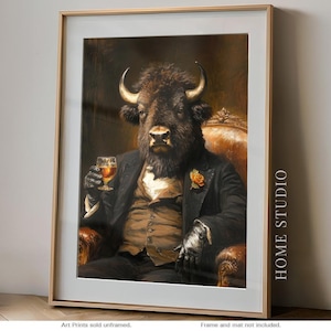 May include: A framed wall art print featuring an anthropomorphic bison dressed in a formal black suit, brown vest, and white shirt, holding a glass of amber liquid while seated in a leather chair. The text HOME STUDIO is printed on the right side.