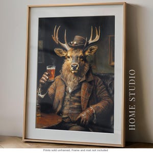 May include: A framed wall art print featuring an anthropomorphic deer wearing a brown plaid suit, a vest, and a small hat. The deer holds a glass of amber liquid while sitting in a leather chair. The text HOME STUDIO is printed on the right side.