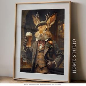 May include: A framed wall art print featuring an anthropomorphic rabbit with antlers wearing a brown plaid suit, a flat cap, and a bowtie, holding a glass of beer. The rabbit has a flower pinned to the lapel. The text HOME STUDIO is visible.
