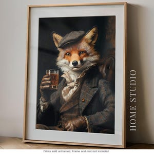 May include: A framed wall art print featuring an anthropomorphic fox wearing a brown tweed flat cap, a matching plaid blazer, and a light-colored cravat. The fox holds a glass of amber liquid in a gloved hand. The text HOME STUDIO is printed vertically.