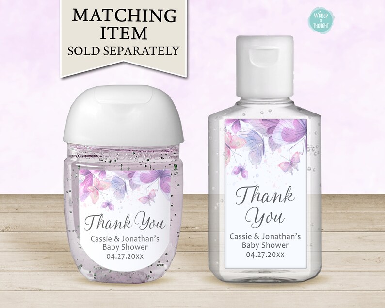 Op de afbeelding: Twee doorzichtige plastic flesjes handdesinfectie met etiketten met een aquarelontwerp van paarse vlinders en de tekst "Bedankt" met de namen Cassie & Jonathan's Baby Shower en de datum 04.27.20xx.