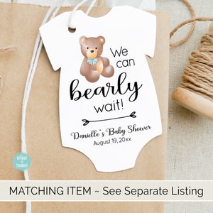 Puede incluir: Etiqueta blanca en forma de body de beb&eacute; con un oso de peluche marr&oacute;n que lleva una pajarita azul. La etiqueta dice "We can bearly wait!" y "Danielle's Baby Shower August 19, 20xx".