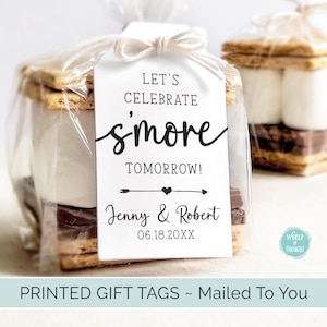 May include: White gift tag with black text that reads "Let's Celebrate smore Tomorrow!" with a small arrow and heart design. Below the text is "Jenny & Robert" and the date "06.18.20XX".