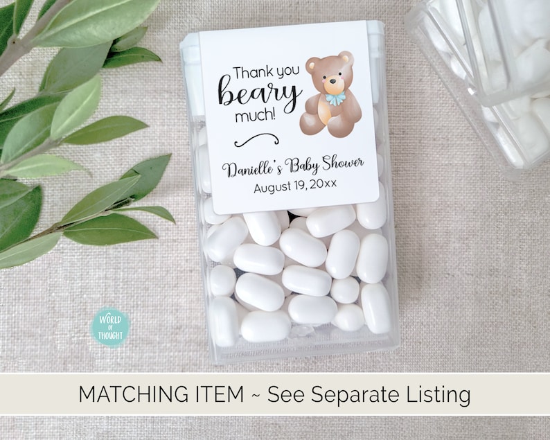 Puede incluir: Un recipiente de pl&aacute;stico transparente lleno de mentas blancas. Una etiqueta blanca con una ilustraci&oacute;n de un oso de peluche marr&oacute;n y el texto "Thank you beary much! Danielle's Baby Shower August 19, 20xx" est&aacute; pegada al recipiente.