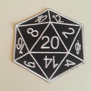 Op de afbeelding: Zwart-wit geborduurde patch van een twintigzijdige dobbelsteen, ook wel een d20 genoemd. De nummers 4, 6, 8, 10, 12, 14, 16, 17, 18, 19 en 20 zijn zichtbaar op de dobbelsteen.