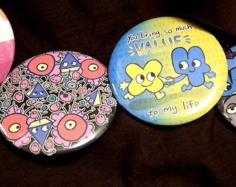 May include: A collection of five colorful, round pinback buttons. The buttons feature various cartoon characters and phrases, including "No Straw Needed" and "You bring so much VALUE to my life."