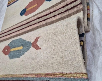 May include: Off-white woven rug with fish motifs. The rug features colorful fish designs in pink, blue, and yellow, along with striped borders in various colors. The text "ATAhomedecore" is visible.