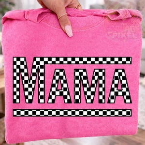 May include: A pink sweatshirt with the word "MAMA" in large, bold, black letters. The letters are filled with a black and white checkered pattern. The word is framed by a black and white checkered border.