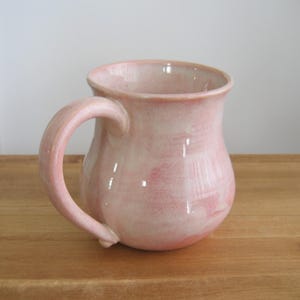 May include: A white ceramic mug with a black handle and the text "But First, Coffee" in a black, bold font. The mug is likely 4 inches tall and holds approximately 12 ounces of liquid.