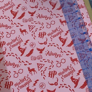 May include: Pink wrapping paper with a repeating pattern of Harry Potter themed images. The images include the Harry Potter logo, glasses, a lightning bolt, a feather, a deer, footprints, and the words "Always" and "Mischief Managed".