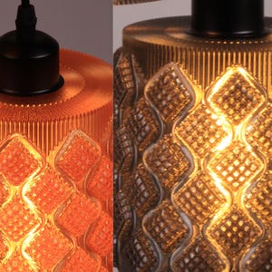 May include: Close-up of two pendant lights with textured glass shades. One is orange, the other is gold. Both have a diamond pattern and a black fixture. The lights are designed for indoor use.